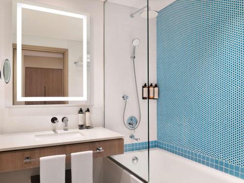 a bathroom with a shower and a sink and a mirror at Mercure Dubai Deira in Dubai