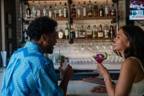 a man and a woman standing at a bar with a drink at OUTRIGGER Waikiki Paradise Hotel in Honolulu