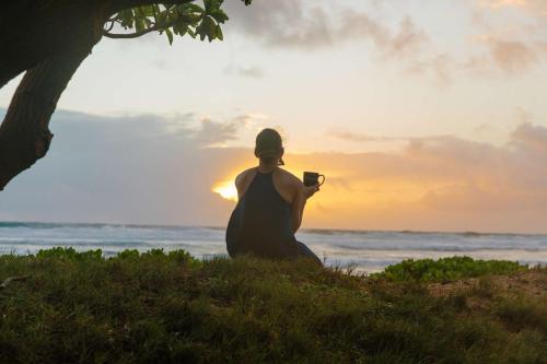 OUTRIGGER Kaua'i Beach Resort & Spa في ليهو: امرأة جالسة على الشاطئ تأخذ صورة للمحيط