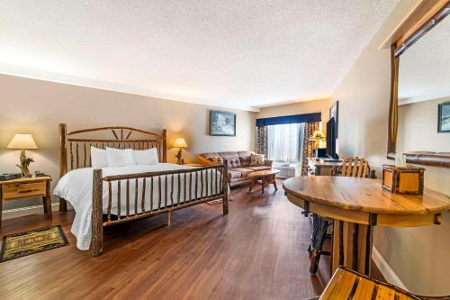 a bedroom with a bed and a living room at Black Bear Inn, Ascend Hotel Collection in Orono