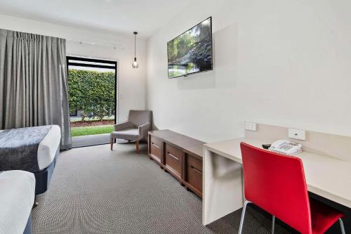 a hotel room with a desk and a bed and a window at Quality Resort Parkhurst in Rockhampton