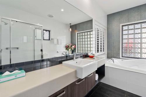 a white bathroom with a sink and a tub and a tubermott at Quality Resort Parkhurst in Rockhampton