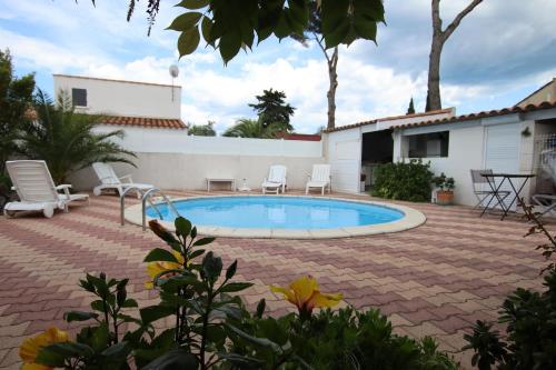 a patio with a pool and chairs and a house at Chambre privée indépendante, piscine in Cap d'Agde