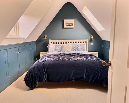 Schlafzimmer mit einem Bett mit blauer Wand in der Unterkunft Luxury farmhouse in secluded Cotswold valley in Uley