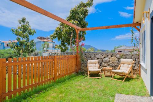 a backyard with two chairs and a fence at Larimar Suite Hotel in Oludeniz