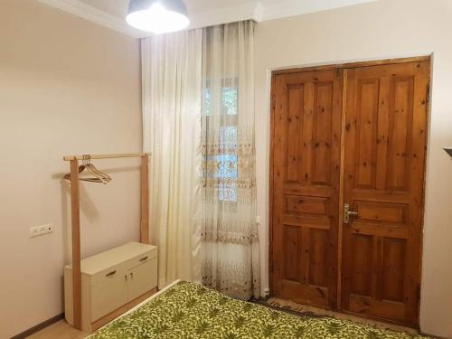 - une chambre avec un lit et une porte en bois dans l'établissement Tkhibuli geust house, à Tqibuli