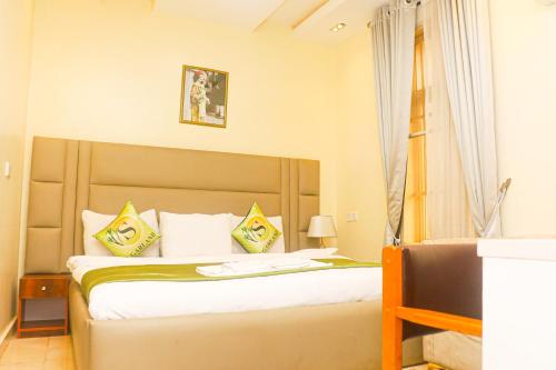 1 dormitorio con 1 cama con almohadas amarillas y blancas en Sugarland Hotel and Suite en Ikeja