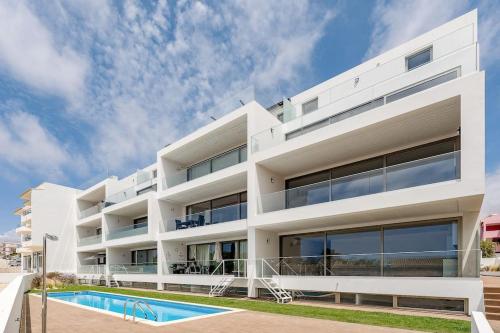 a white apartment building with a swimming pool at Dália modern apartment Five minutes to beach in Luz