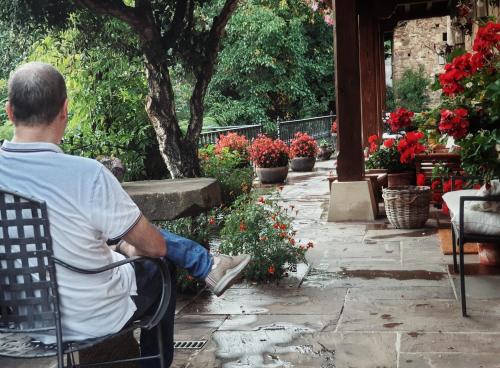 Un uomo seduto su una sedia in giardino di Posada El Azufral a Cambarco