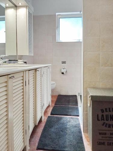 a bathroom with a sink and a toilet and some rugs at Villa Arcadia in Vlakhérna