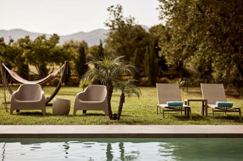 trzy krzesła i palma obok basenu w obiekcie Villa Fuerte Chania - Including Two 7-seater Vans, Airport Shuttle w mieście Alikianós