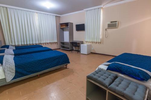 um quarto de hotel com duas camas e um sofá em Alfa Hotel Vespasiano em Vespasiano
