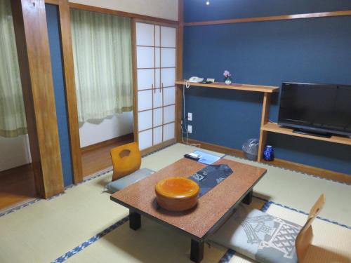 a living room with a table and a tv at 御宿しんしま in Matsuzaki