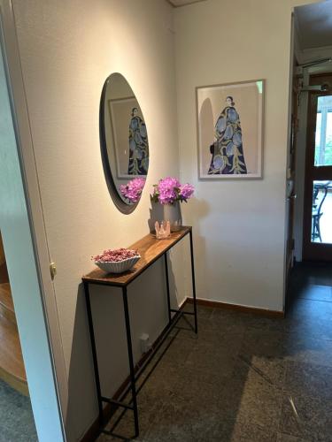 a hallway with a table with a mirror and flowers at Ewa & Maude Hotel in Gothenburg