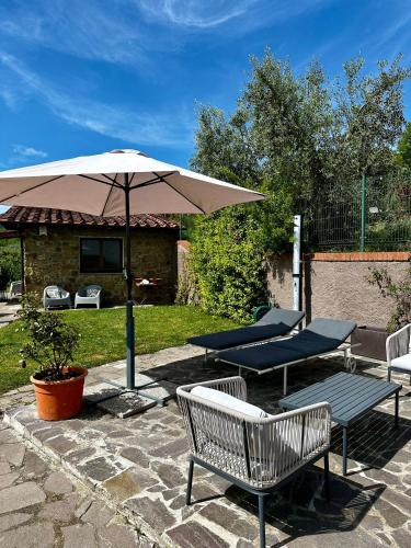 a patio with two chairs and an umbrella at Il Villino del Daino - Toscana in Loro Ciuffenna