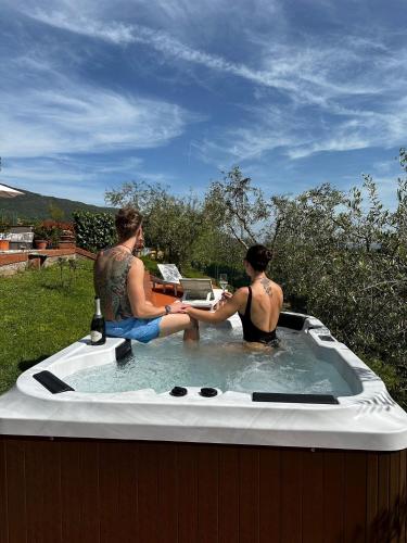 two men are sitting in a hot tub at Il Villino del Daino - Toscana in Loro Ciuffenna
