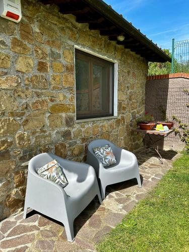 two chairs sitting in front of a stone building at Il Villino del Daino - Toscana in Loro Ciuffenna