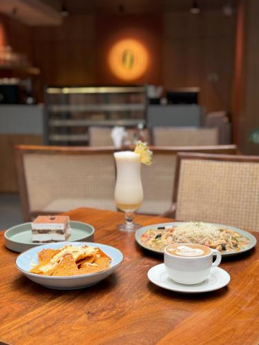 a table with plates of food and a cup of coffee at SKYLA Studios & Suites - Kondapur in Hyderabad