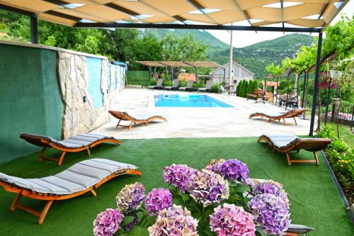 un patio con flores púrpuras y una piscina en Gazdinstvo Vukanović - Kuća za odmor, en Trebinje