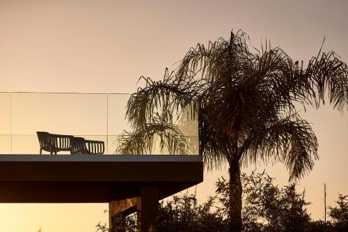 a palm tree and a bench in front of a building at Villa Fuerte Chania - Including Two 7-seater Vans, Airport Shuttle in Alikianós