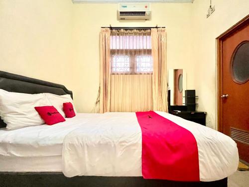 a bedroom with a bed with two red pillows on it at RedDoorz at Hotel Madani Syariah Lempuyangan in Demangan