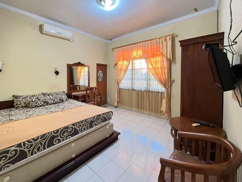 a bedroom with a bed and a tv and a window at RedDoorz at Hotel Madani Syariah Lempuyangan in Demangan