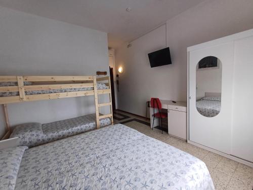1 dormitorio con 2 literas y espejo en Hotel Flora, en Cesenatico