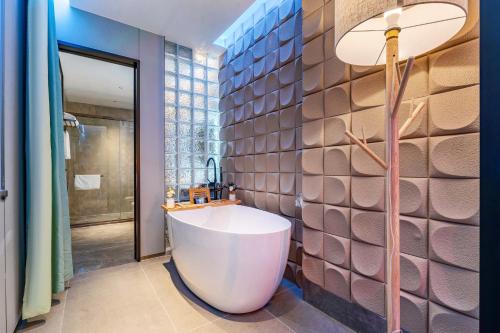baño con una gran bañera blanca y una pared en Henghe Select S Design Hotel - Guangzhou Baixin Square Flagship Store, en Guangzhou