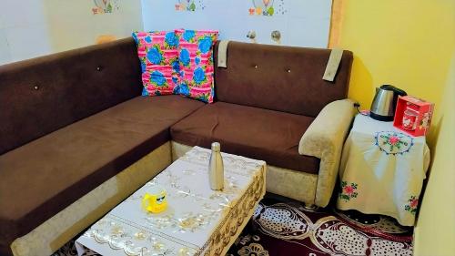 a living room with a brown couch and a table at Shree Hatkeshwar Home Stay Ujjain in Ujjain