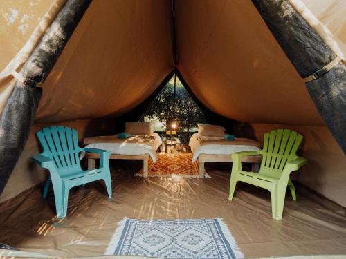 two chairs and a bed in a tent at Firefly Falls in Plettenberg Bay