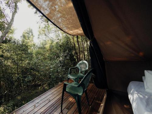 a room with a bed and a chair on a deck at Firefly Falls in Plettenberg Bay