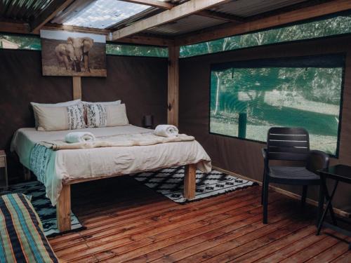 a bedroom with a bed and a chair in a room at Firefly Falls in Plettenberg Bay