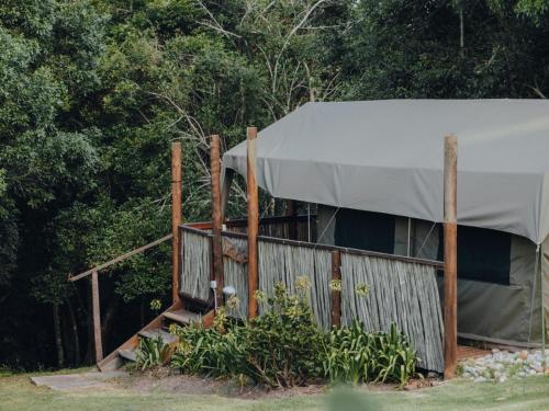 a tent with a fence and trees in the background at Firefly Falls in Plettenberg Bay
