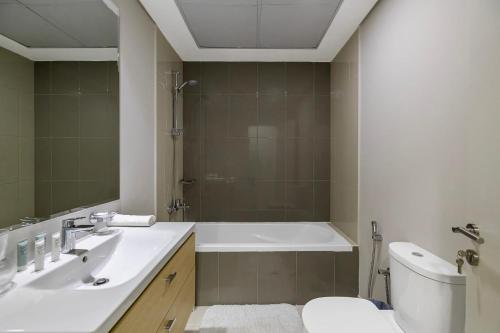 a bathroom with a tub and a sink and a toilet at Studio Huge Balcony Loreto 1 Damac Hills in Dubai Marina
