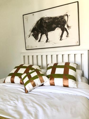 a bed with two pillows and a picture of a horse at Bird Song Cottage - Table View in Cape Town