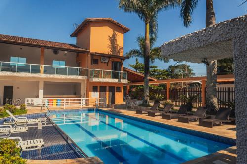 a villa with a swimming pool and palm trees at Pousada Acqua Bella PISCINA CLIMATIZADA in Bertioga
