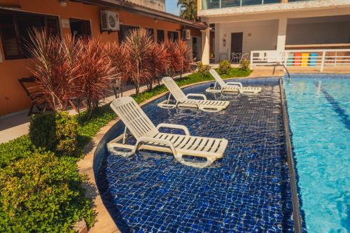 a group of lounge chairs next to a swimming pool at Pousada Acqua Bella PISCINA CLIMATIZADA in Bertioga
