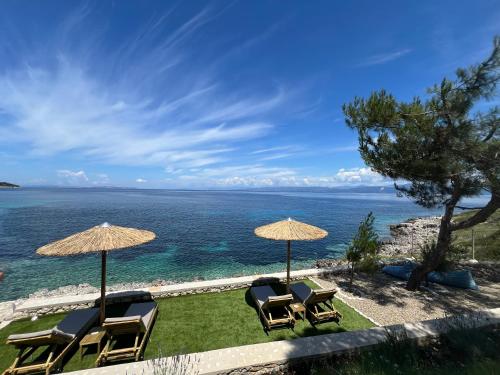 a group of chairs and umbrellas on the beach at Paxos Sunrise Villas in Gaios
