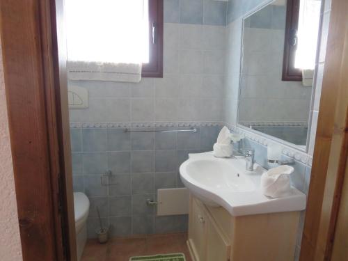 bagno con lavandino, servizi igienici e specchio di Villetta Sunrise 6A a Costa Rei
