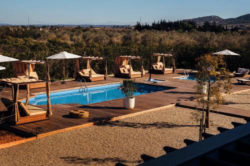 uma piscina com cadeiras e guarda-sóis ao lado em La Farm Baleares em Santa Maria del Camí