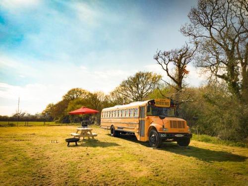 a school bus parked in a field with a picnic table at American School Bus Glamping with Hot Tub in Woolacombe! in Lee