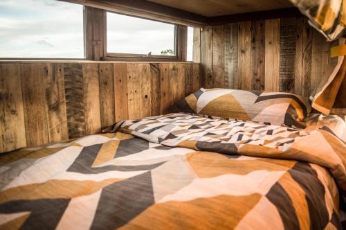 a bedroom with a bed with a comforter and a window at American School Bus Glamping with Hot Tub in Woolacombe! in Lee