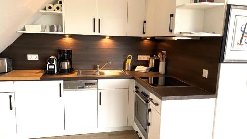 a kitchen with white cabinets and a sink at Appartement Backbord in Morsum