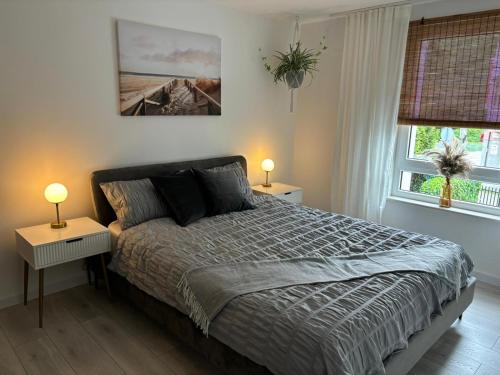 赫爾的住宿－White Shell Apartament Hel，一间卧室配有一张带两张桌子和两盏灯的床。