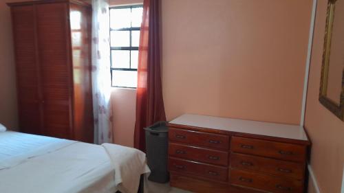 ein Schlafzimmer mit einem Bett, einer Kommode und einem Fenster in der Unterkunft Angie's Cove, modern get-away overlooking Castries in Castries