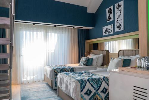 a hotel room with two beds and blue walls at Royal Wings Hotel in Lara