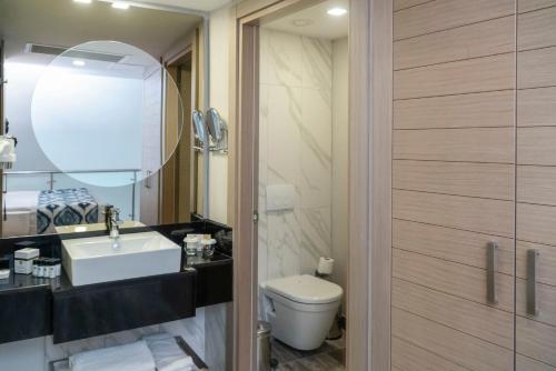 a bathroom with a sink and a toilet and a mirror at Royal Wings Hotel in Lara
