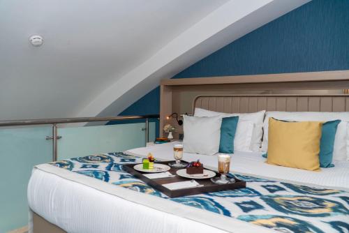 a bedroom with a bed with a tray of food on it at Royal Wings Hotel in Lara