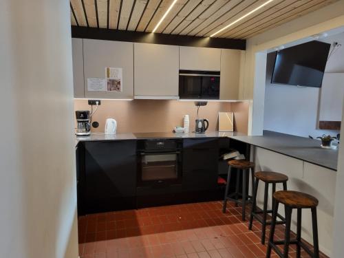 una cocina con electrodomésticos negros y 2 taburetes en Outdoor Hostel Laajis, en Jyväskylä