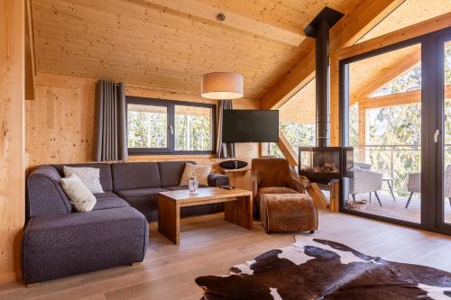 ein Wohnzimmer mit einem Sofa und einem TV in der Unterkunft Alpenchalets Reiteralm by ALPS RESORTS in Schladming